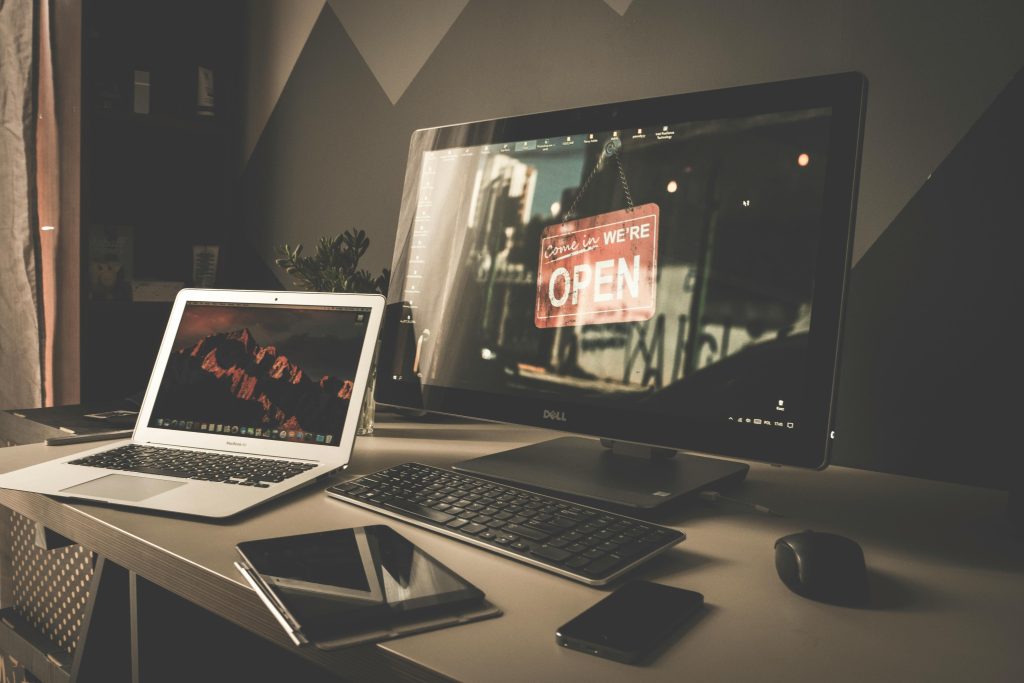 Stylish and organized workspace featuring a laptop, monitor, and digital devices on a desk.